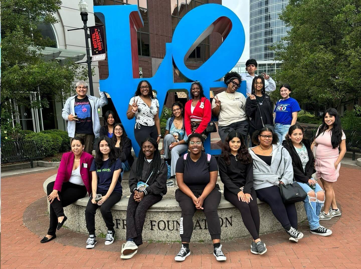 Group photo of students and staff smiling in front of "LOVE" sculpture